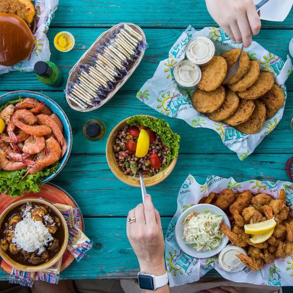 Aerial view of seafood and drinks on a blue picnic table at LuLu's waterfront restaurant in Gulf Shores
