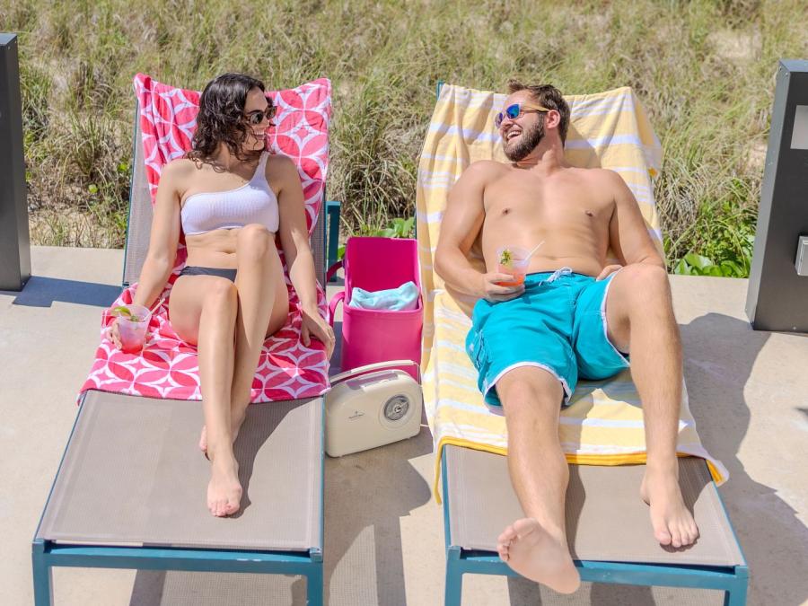 Couple lounging on chairs with cocktails by the pool at The Lodge